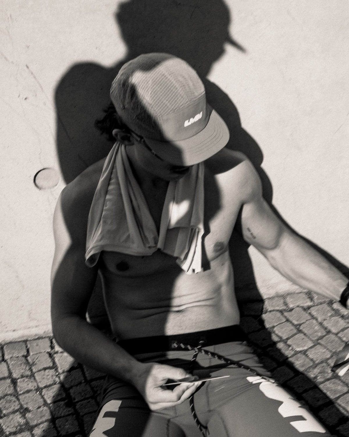 Runner resting in a LUMEN cap, photographed in black and white